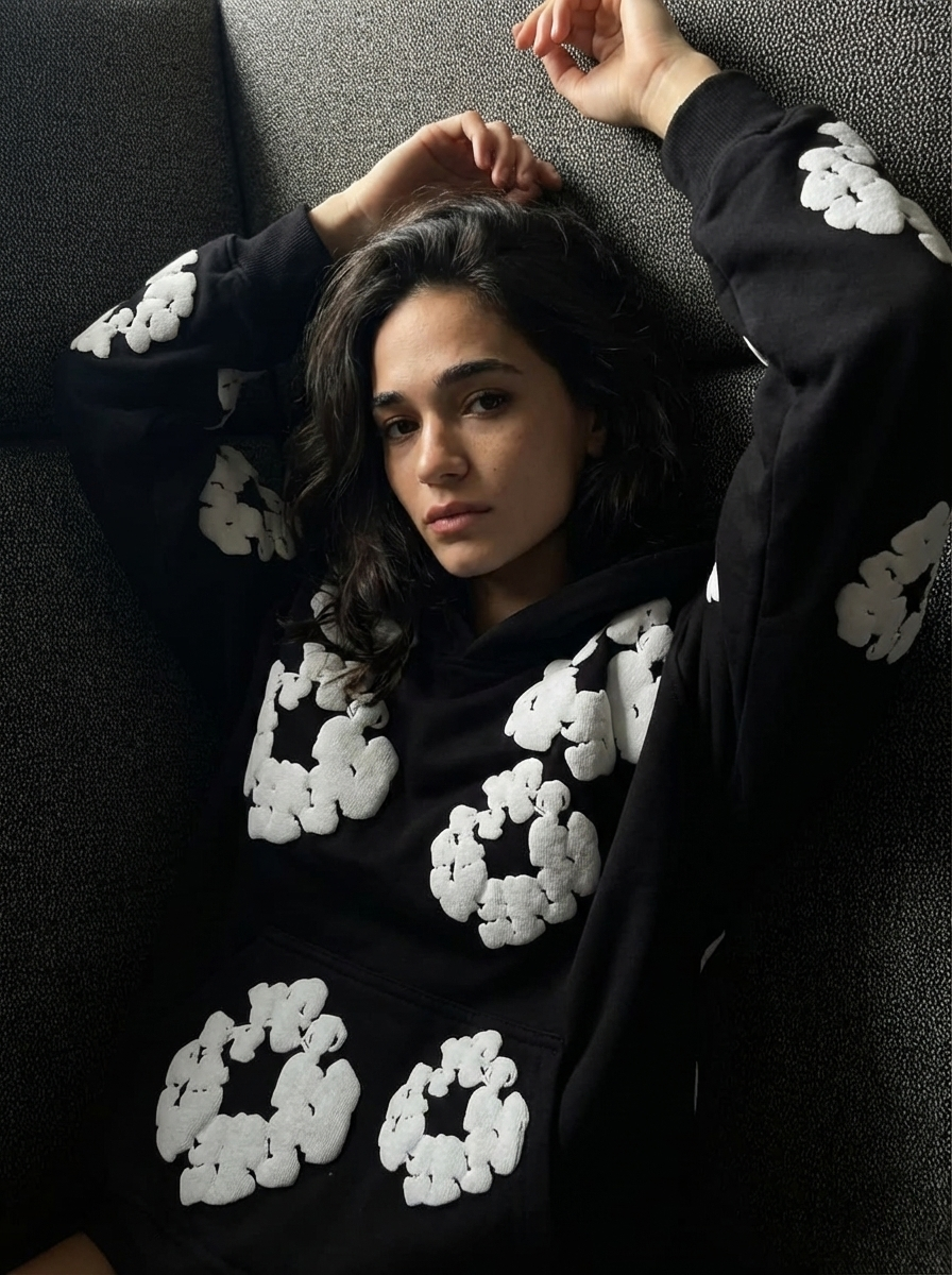 Person wearing a black sweater with white patterns, lying on a gray couch.