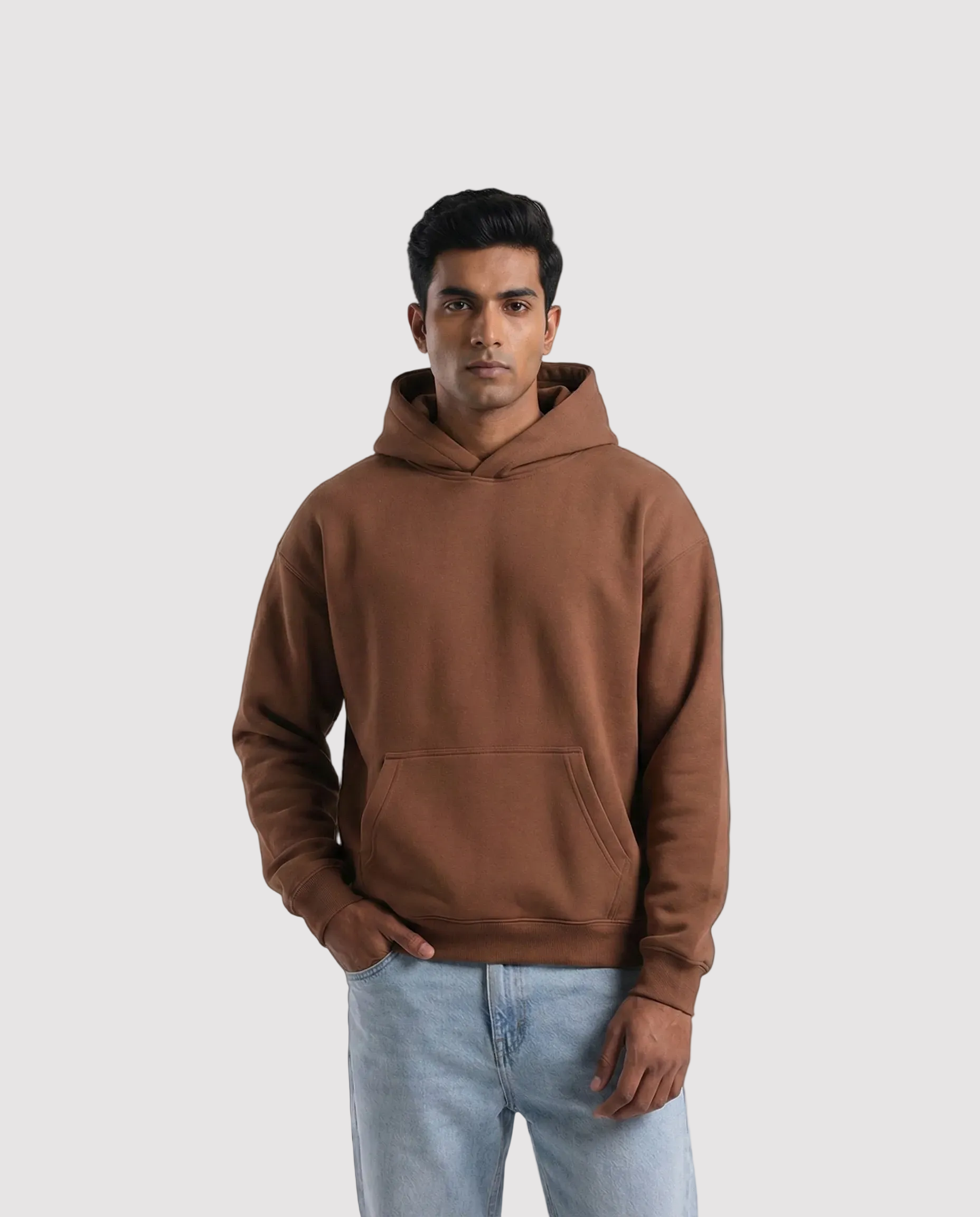 Man wearing a brown hoodie and light blue jeans on a white background